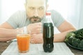 Deep confusing man sitting and looking at cola. Royalty Free Stock Photo