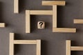 Maze or labyrinth made with wooden blocks with a wooden cube with question mark in the middle. Business strategy, problem solving