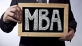 MBA written on blackboard, business person holding sign, business education Royalty Free Stock Photo