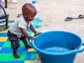 African baby wanting bathing in a basin in a poor suburb of Mbour Royalty Free Stock Photo