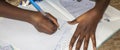 Unidentified young child writing letter to godfather or godmother. Close-up on hands