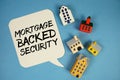MBS Mortgage-backed Security text with house models on blue background Royalty Free Stock Photo