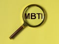 MBTI test of personality types. Acronym through magnifying lens on yellow background. Psychology concept