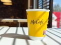Mccafe yellow coffee cup on sunlit table in cafe environment Royalty Free Stock Photo