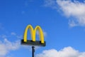 McDonald\'s Logo Against Blue Sky and White Clouds Royalty Free Stock Photo