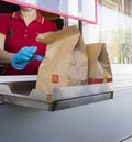 McDonalds service the Drive-Thru due to coronavirus. Employee in gloves, order in window. Contactless transfer