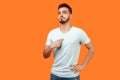 This is me! Portrait of arrogant self-confident brunette man pointing at his chest. isolated on orange background