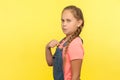 This is me! Portrait of egoistic self-confident little girl in denim overall pointing herself and looking with arrogance