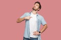 This is me. Portrait of proud haughty handsome bearded young man in blue casual style shirt standing, looking away and pointing Royalty Free Stock Photo