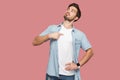 This is me. Portrait of proud haughty handsome bearded young man in blue casual style shirt standing, looking away and pointing