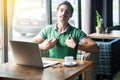 This is me! Young proud haughty businessman in green t-shirt sitting with laptop and looking at camera with proud confident face