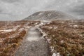 Meabh`s Cairn, at the summit of Knoncknarea hill, county Sligo, Ireland at winter season. Snow fall, Cloudy sky in the background