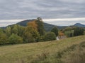 Meadow with autumn colorful forest, trees and hills and country rustic house, moody sky. Landscape in Luzicke hory Royalty Free Stock Photo