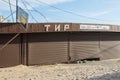 Meadow covered pavilion with a broken roller shutters and the signboard Tir, sanded in the offseason