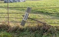 meadow with fence and a tipped over sign showing the german words \