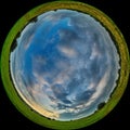 Meadow with green grass and clouds in the sky. Shot through a circular fisheye lens