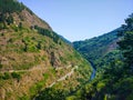 Meadow of a road in middle of a hillside of a mountain with a ri