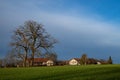 Deep, fresh blue sky with white clouds over landscape with single oak tree, vegetation and rural house Royalty Free Stock Photo