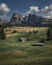 Meadows with wooden cabins at Alpe di Siusi during summer with view to mountains of Plattkofel and Langkofel in the Dolomite Alps Royalty Free Stock Photo