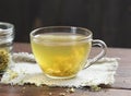 Meadowsweet floral herbal tea in glass cup with dried herb in a jar nearby on the wooden rustic table Royalty Free Stock Photo