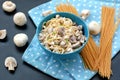 Meal from pasta spaghetti, mushroom, cottage cheese and parsley in blue bowl on dot cloth on black background