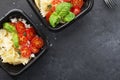 Meal prep. Black lunch boxes. Pasta bows, cherry tomatoes, young cheese, salt, pepper, basil. On a dark background Top Royalty Free Stock Photo