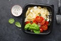 Meal prep. Black lunch boxes. Pasta bows, cherry tomatoes, young cheese, salt, pepper, basil. On a dark background Top Royalty Free Stock Photo