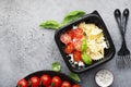 Meal prep. Black lunch boxes. Pasta bows, cherry tomatoes, young cheese, salt, pepper, basil. On a dark background Top Royalty Free Stock Photo