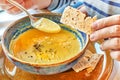 Meal, hands with a spoon and toast over a plate with pumpkin soup