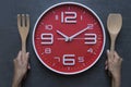 Meal time with alarm clock, hand holding spoon and fork