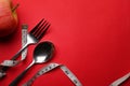 Measure tape, spoon fork and apple on red background. Loss weight and healthy diet concept. Royalty Free Stock Photo