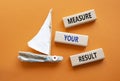 Measure your Result symbol. Concept words Measure your Result on wooden blocks. Beautiful orange background with boat. Business Royalty Free Stock Photo