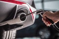 Measurement of exhaust emissions at the technical inspection station. A car repairman applies a probe to the exhaust