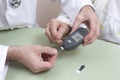 Measurement of the glucose meter with an old woman. The doctor`s hands hold a black glucometer. Royalty Free Stock Photo