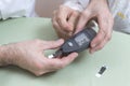 Measurement of the glucose meter with an old woman. The doctor`s hands hold a black glucometer. Royalty Free Stock Photo