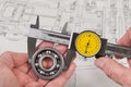 Measurement of steel ball bearing by precise analog caliper above a technical drawing Royalty Free Stock Photo