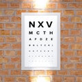 Measurement table of sight. Framework hanging on a brick wall. View examination. Letters in block letters. Eye test.