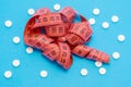 Measuring centimeter tape is on blue background surrounded by white round tablets. Concept photo pharmacological weight loss and