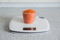 Measuring cup with red lentil on digital kitchen scales on kitchen table Royalty Free Stock Photo