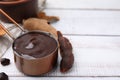 Measuring cup with tasty tamarind sauce and fresh pods on white wooden table. Space for text