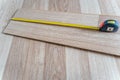 Measuring Laminate Wooden Floor Board with Yellow Measure Tape for Room Reconstruction Royalty Free Stock Photo