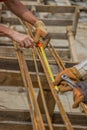 Measuring and marking steel rods for making beam cages at construction site