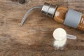 Measuring scoop of protein powder and bottle with shake on wooden table. Space for text Royalty Free Stock Photo