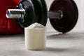 Measuring scoop of protein powder and dumbbell on white table Royalty Free Stock Photo