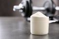 Measuring scoop of protein powder on grey table. Royalty Free Stock Photo