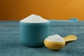 Measuring scoops of protein powder on blue table, closeup