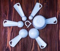 Measuring set table spoons and cups plastic white color on wooden background. Devices, measuring ingredients for cooking Royalty Free Stock Photo