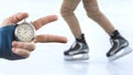 Measuring speed on skates with a stopwatch. hand with a stopwatch on the background of the legs of a man skating on an ice rink