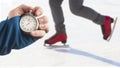 Measuring speed on skates with a stopwatch. hand with a stopwatch on the background of the legs of a man skating on an ice rink