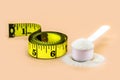 Measuring spoon with creatine, whey or casein, whey supplements, with tape measure beside, copyspace